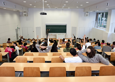 Students raising hands in a college class